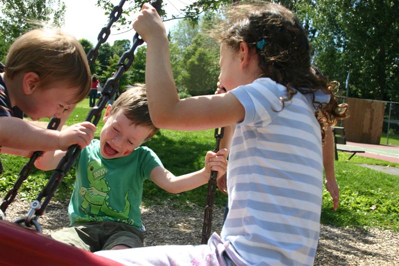 All three kids on a tire swing